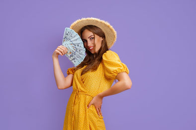 woman in yellow dress holding up a fan of money.