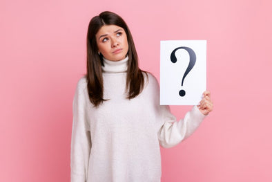 woman holding up paper sign with question mark